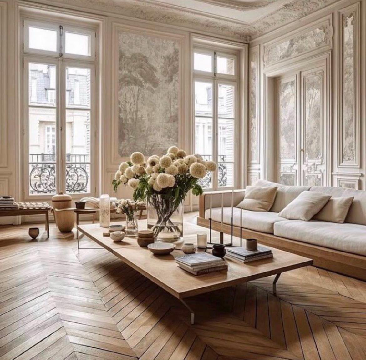 Sala elegante con muebles de madera, flores y luz natural. Suelo en espiga.
